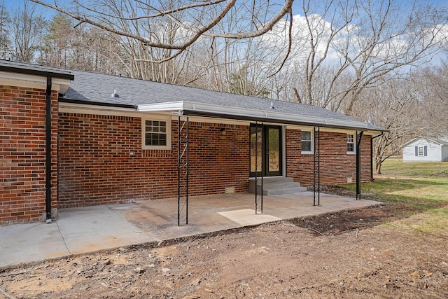 rear view of property with brick siding, a patio area, french doors, and a shingled roof