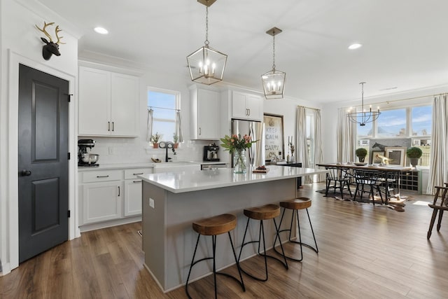 kitchen featuring freestanding refrigerator, a sink, a chandelier, a kitchen bar, and plenty of natural light