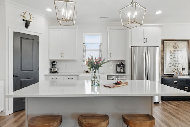 kitchen featuring a chandelier, a kitchen bar, white cabinetry, light countertops, and backsplash