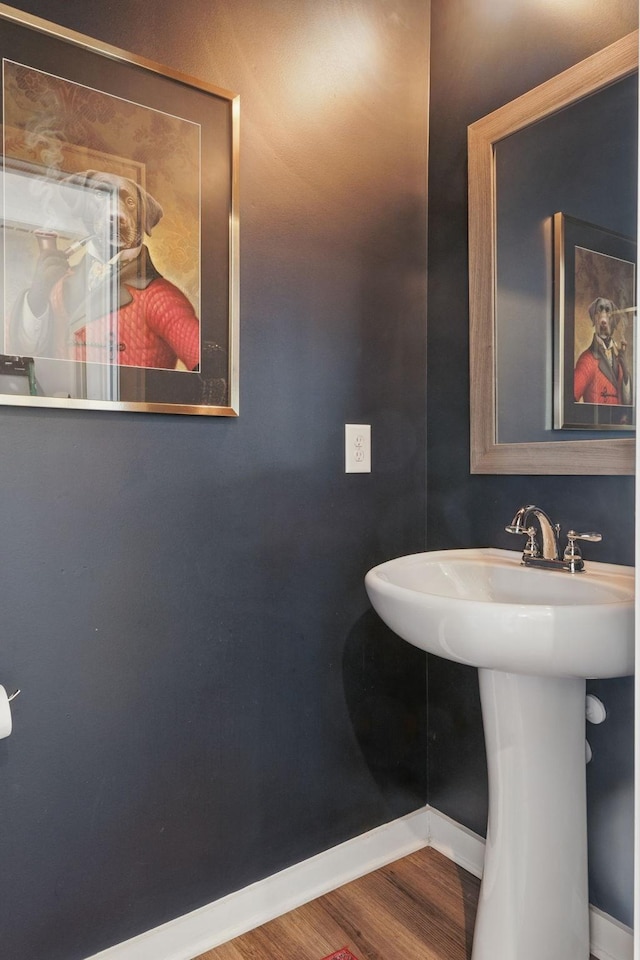 bathroom featuring baseboards, wood finished floors, and a sink