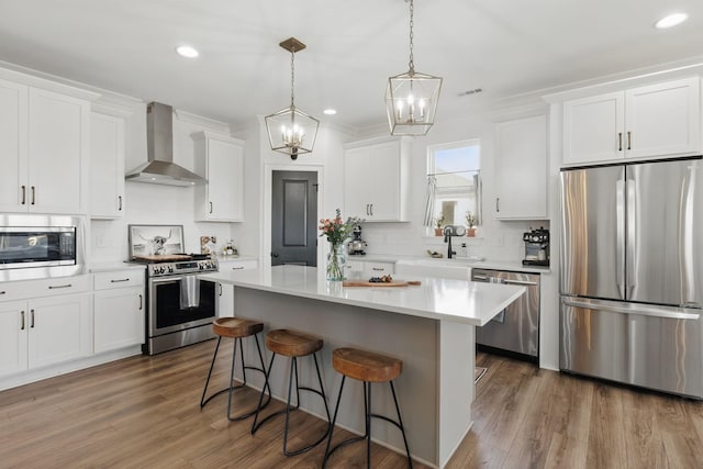 kitchen with stainless steel appliances, wall chimney exhaust hood, a sink, a chandelier, and tasteful backsplash