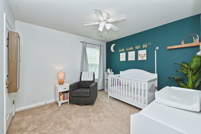 bedroom featuring carpet flooring, a nursery area, baseboards, and ceiling fan