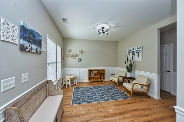 sitting room with visible vents, wood finished floors, and wainscoting