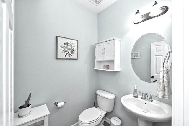 half bath with a sink, visible vents, baseboards, and toilet