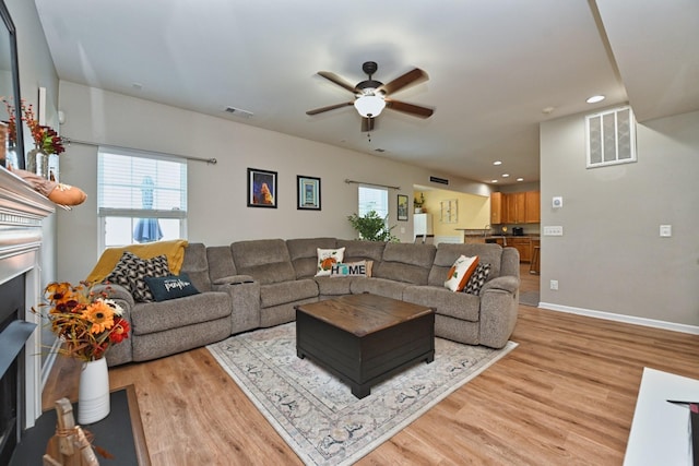 living area featuring visible vents, light wood-style floors, a healthy amount of sunlight, and a fireplace