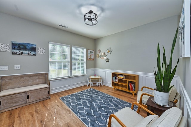 sitting room with visible vents, wainscoting, and wood finished floors