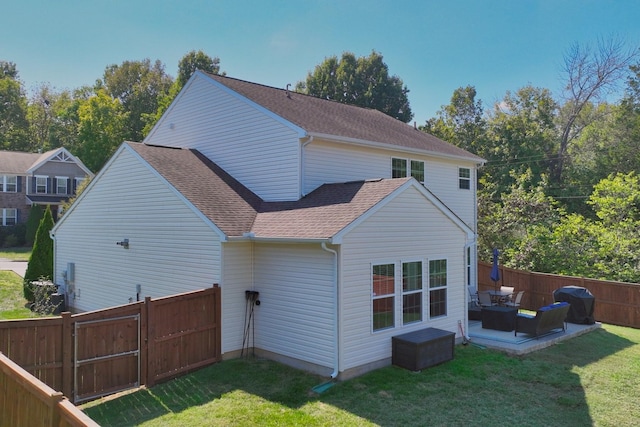 back of property featuring a yard, a patio area, a shingled roof, and fence