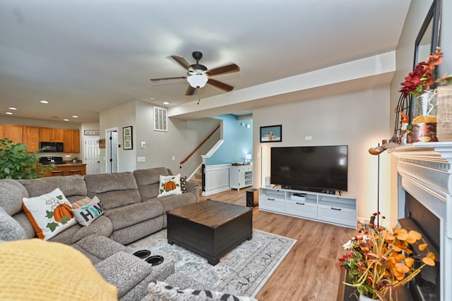 living room featuring light wood finished floors, visible vents, stairs, recessed lighting, and a fireplace