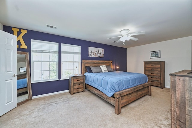 bedroom featuring visible vents, baseboards, light colored carpet, and a ceiling fan