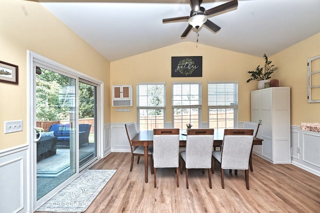 dining area featuring a wainscoted wall, vaulted ceiling, and light wood-type flooring