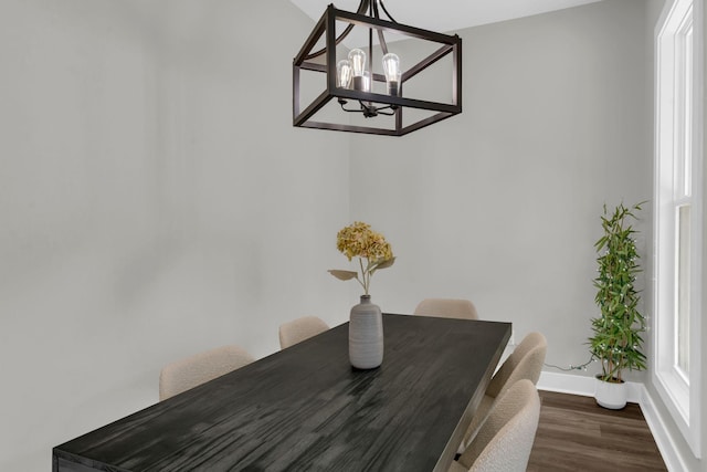 unfurnished dining area featuring an inviting chandelier, baseboards, dark wood-style flooring, and a wealth of natural light