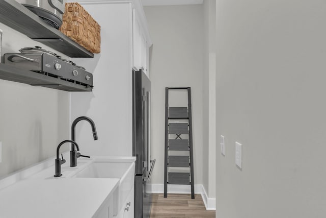 kitchen featuring freestanding refrigerator, light wood-style floors, white cabinets, light countertops, and baseboards