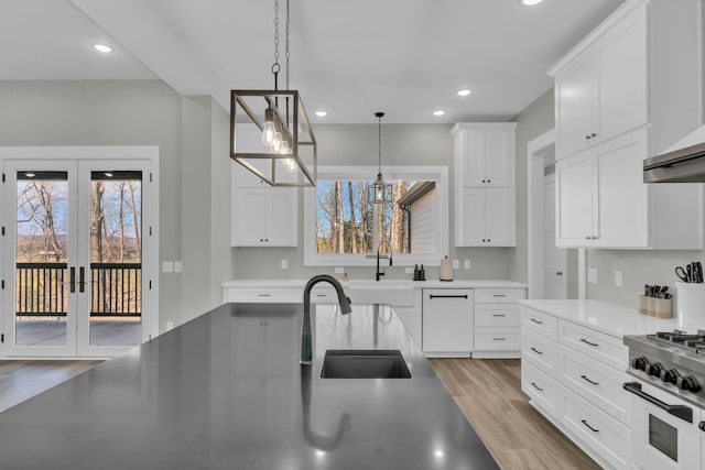 kitchen with a sink, dishwasher, wood finished floors, white cabinetry, and range