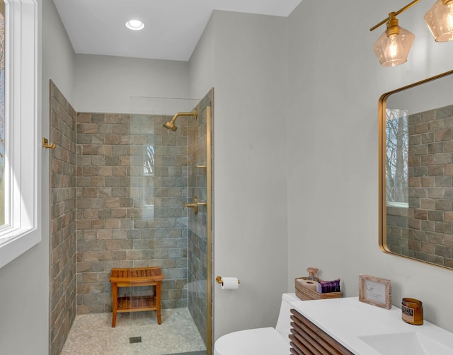 full bathroom with toilet, tiled shower, and vanity