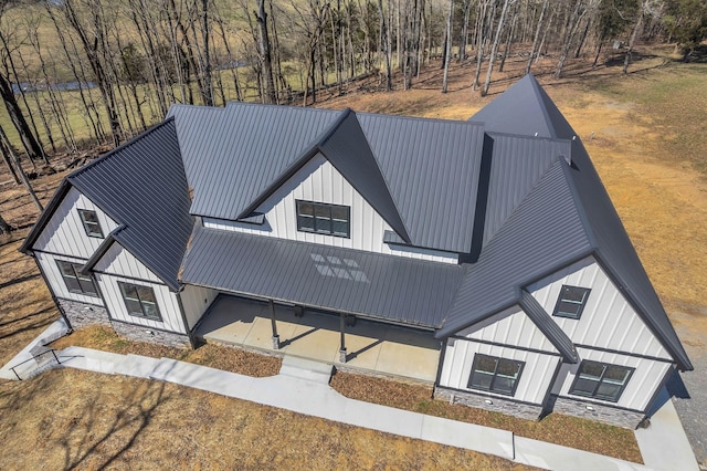 modern inspired farmhouse with stone siding, board and batten siding, metal roof, and a standing seam roof