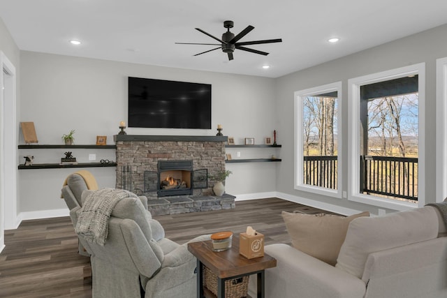 living room featuring a stone fireplace, recessed lighting, baseboards, and wood finished floors