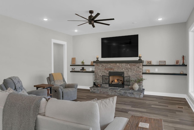 living area with wood finished floors, baseboards, a ceiling fan, recessed lighting, and a stone fireplace