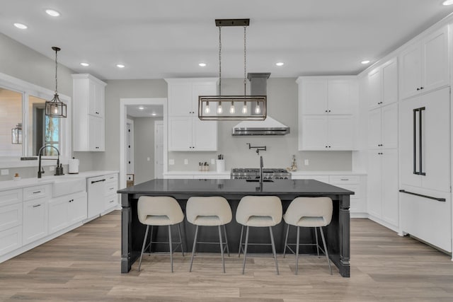 kitchen featuring built in fridge, white cabinets, light wood-style flooring, and a sink