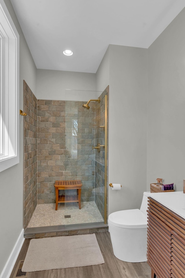 full bath featuring visible vents, toilet, wood finished floors, tiled shower, and baseboards