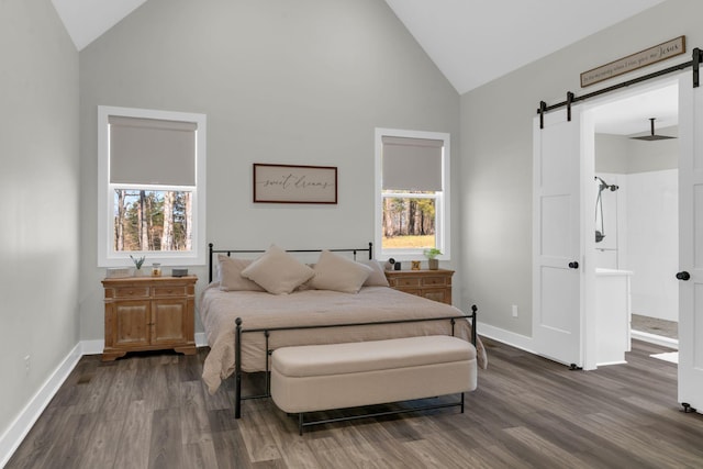 bedroom featuring a barn door, multiple windows, baseboards, and dark wood-style flooring