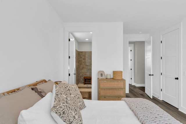 bedroom with connected bathroom, baseboards, and dark wood finished floors