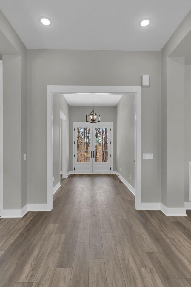 interior space with an inviting chandelier, french doors, baseboards, and dark wood-style flooring