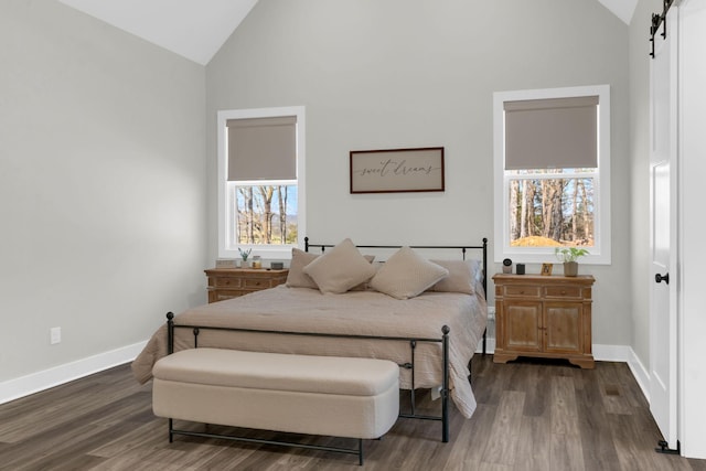 bedroom with a barn door, wood finished floors, and baseboards