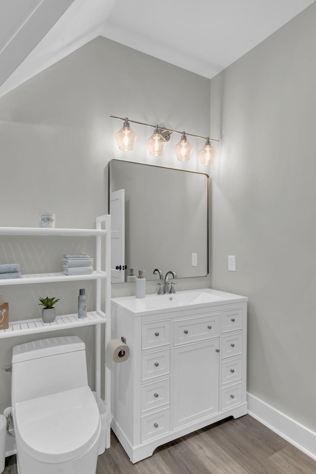 bathroom with vanity, wood finished floors, baseboards, vaulted ceiling, and toilet