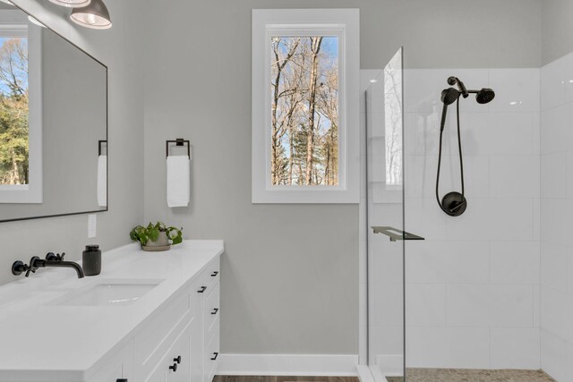 bathroom featuring baseboards, plenty of natural light, vanity, and walk in shower