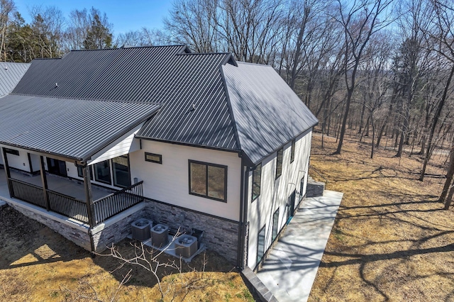 view of side of home featuring central AC and metal roof