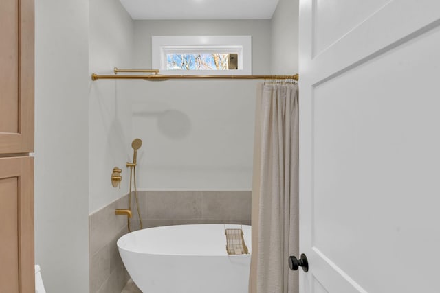 full bath featuring wainscoting, tile walls, and a freestanding tub