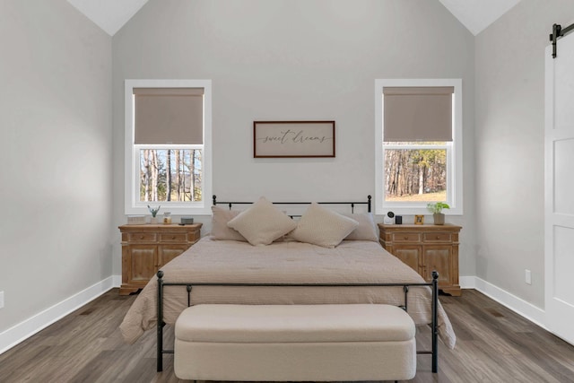 bedroom featuring baseboards, dark wood-type flooring, a barn door, and vaulted ceiling