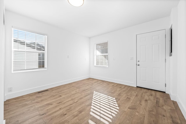 spare room with visible vents, baseboards, light wood-type flooring, and a wealth of natural light