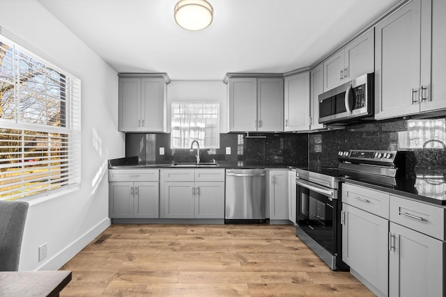 kitchen with dark countertops, gray cabinets, appliances with stainless steel finishes, and a sink