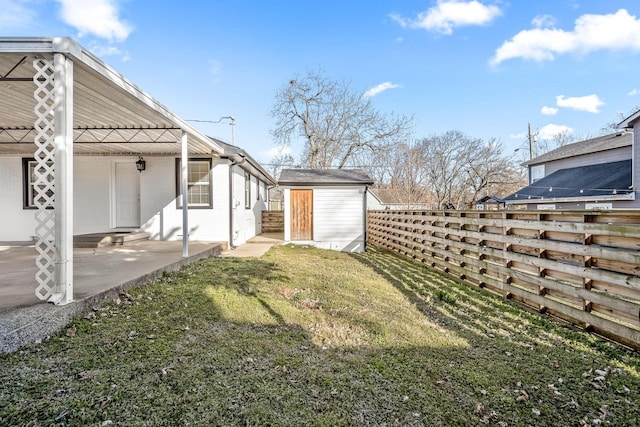 view of yard featuring an outbuilding, a storage shed, a patio, and a fenced backyard