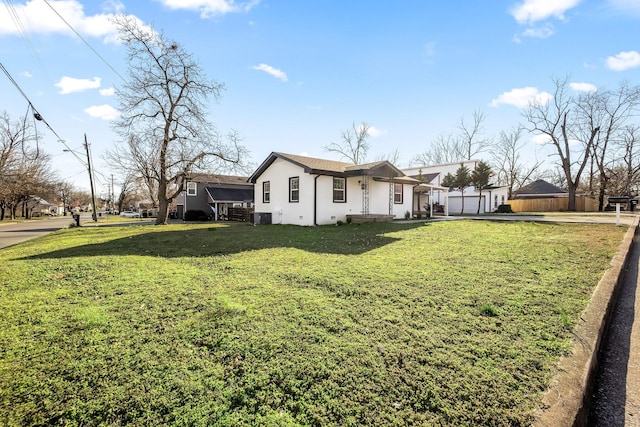 view of side of property featuring a yard, central AC unit, fence, and stucco siding