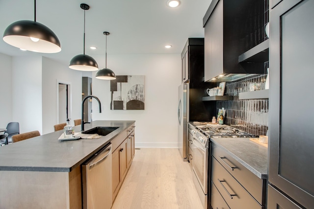 kitchen featuring tasteful backsplash, light wood finished floors, an island with sink, appliances with stainless steel finishes, and a sink