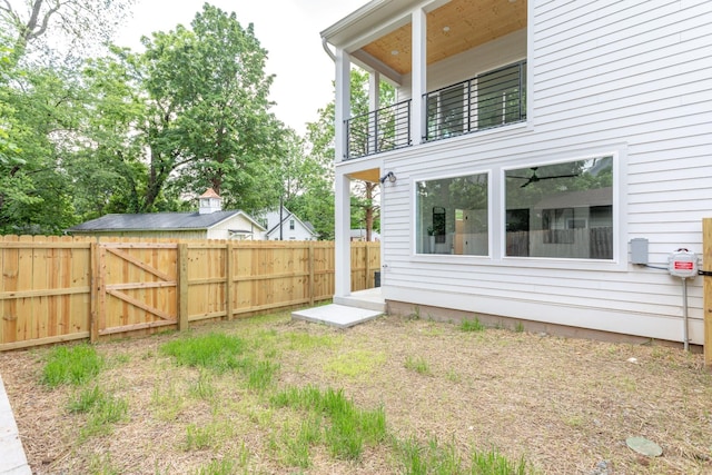 view of yard featuring a gate, a balcony, and fence