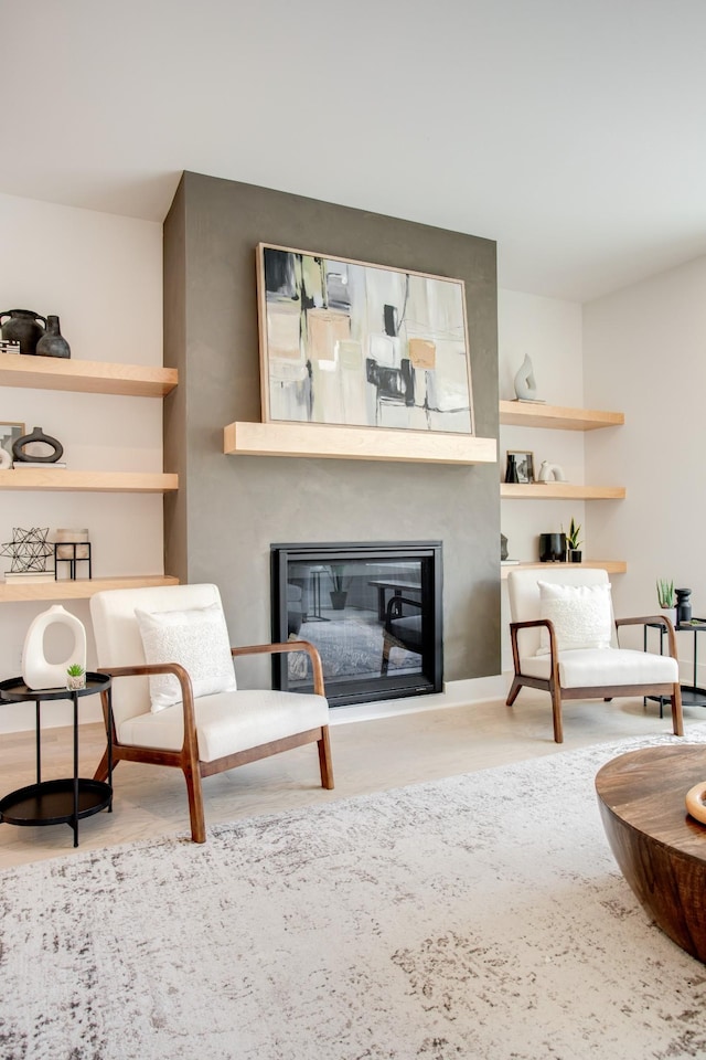 living area featuring wood finished floors and a glass covered fireplace