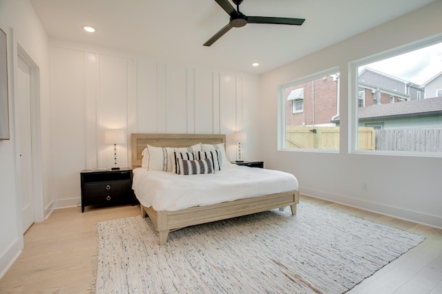 bedroom with recessed lighting, a decorative wall, and light wood finished floors