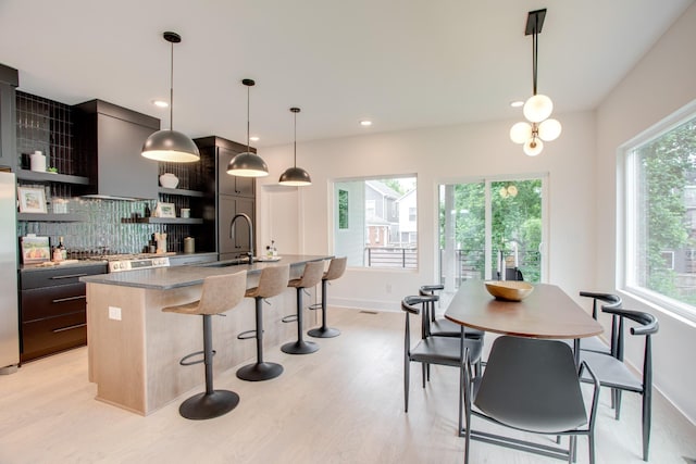 kitchen featuring a kitchen bar, a center island with sink, a sink, open shelves, and extractor fan