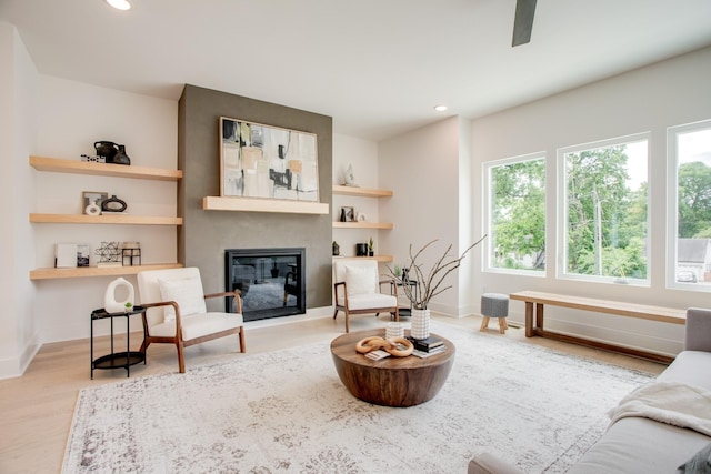 interior space with a glass covered fireplace, recessed lighting, wood finished floors, and baseboards