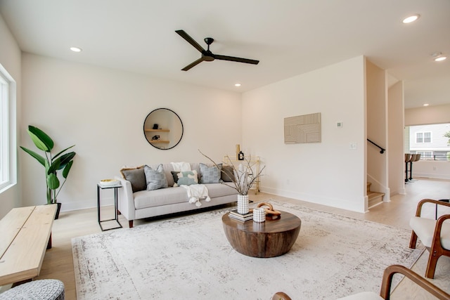 living room with light wood-style flooring, a ceiling fan, recessed lighting, stairway, and baseboards