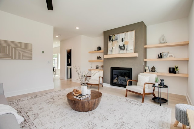 living area featuring a fireplace, recessed lighting, wood finished floors, and baseboards