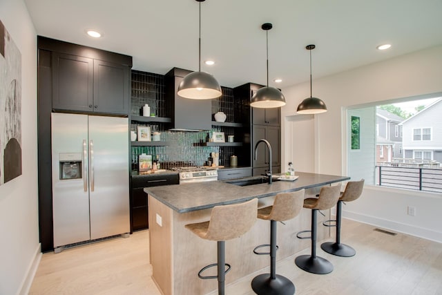 kitchen featuring light wood-type flooring, decorative backsplash, exhaust hood, stainless steel appliances, and a sink