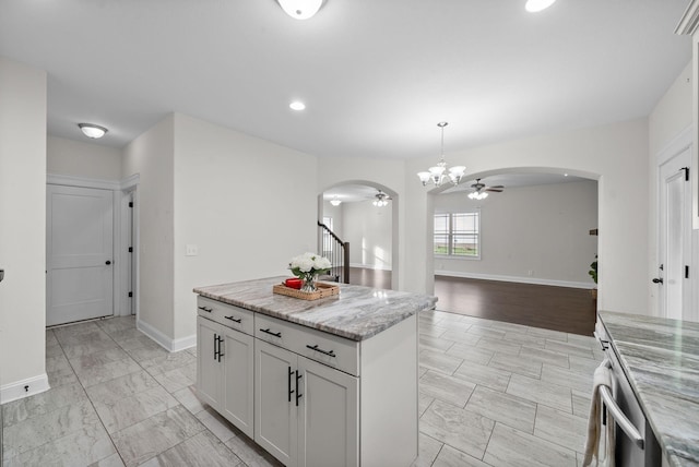 kitchen featuring a ceiling fan, baseboards, arched walkways, decorative light fixtures, and marble finish floor