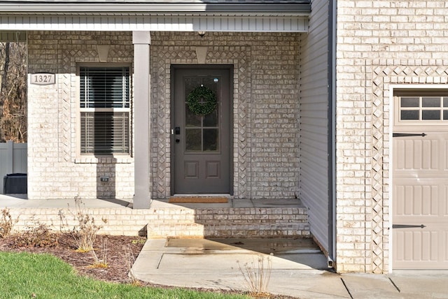 entrance to property with a garage, brick siding, and covered porch