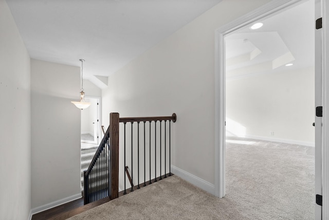 stairway featuring baseboards, carpet, and a raised ceiling