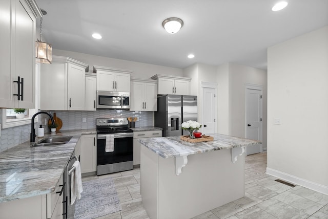 kitchen featuring a kitchen bar, a sink, a kitchen island, appliances with stainless steel finishes, and decorative backsplash