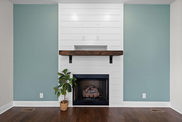 room details featuring visible vents, baseboards, wood finished floors, and a fireplace